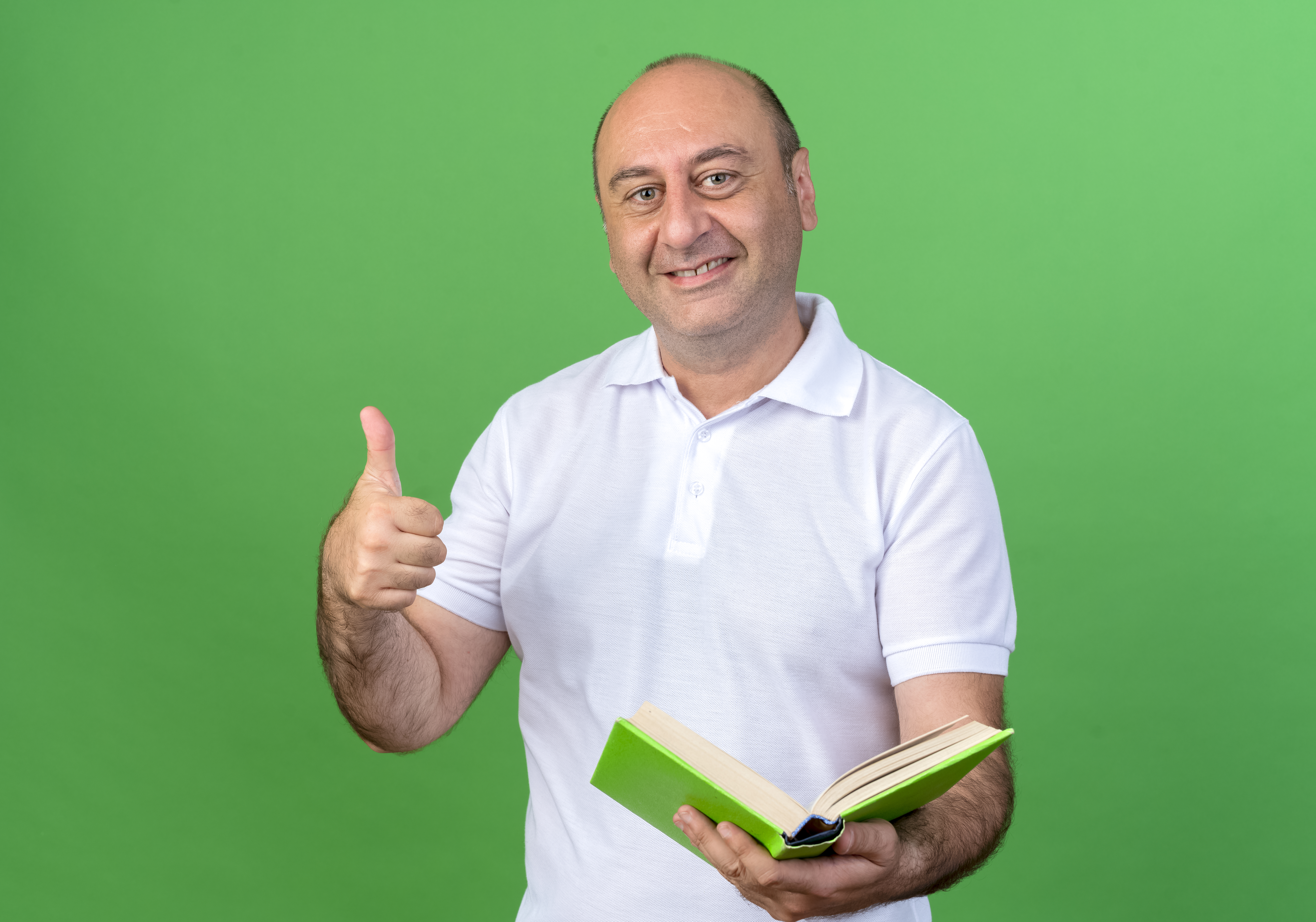 smiling casual mature man holding book his thumb up isolated on green background